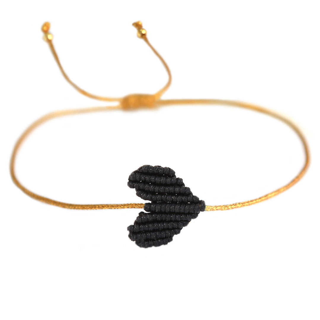 Armband mit goldenem Band und geflochtenem Herz in schwarz von Love Ibiza. Dank praktischem Schiebeknoten passt das Armband an jedes Handgelenk!