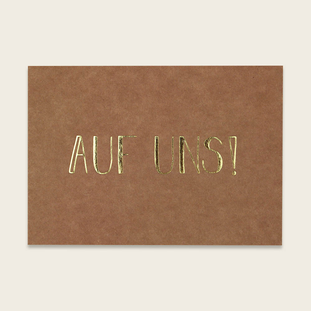 Postkarte "Auf uns!" in rostbraun von Ava & Yves - gedruckt auf hochwertiger Holzschliffpappe mit Goldveredlung. Rückseite blanko.