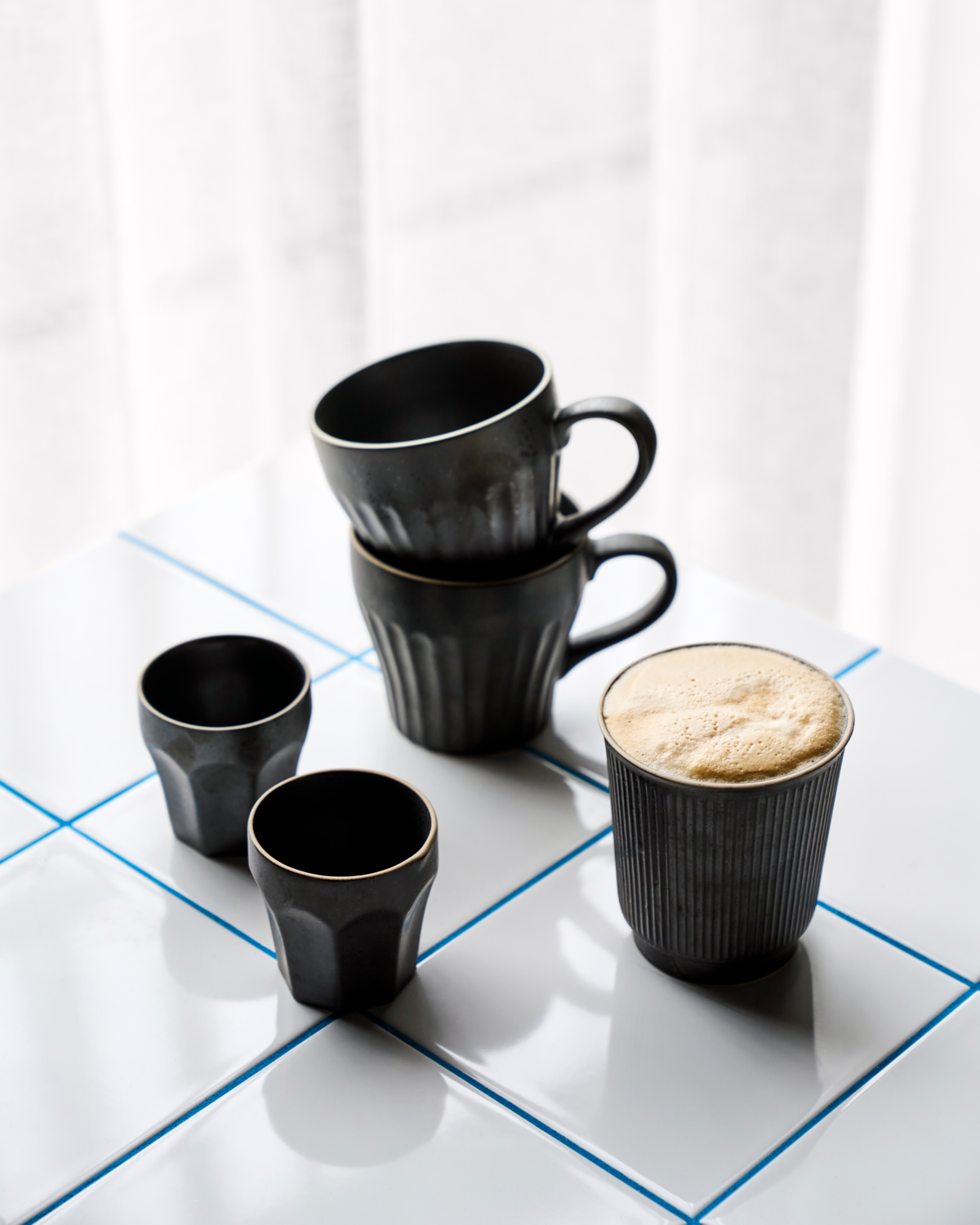 Becher "Berica" in schwarz von House Doctor aus Steingut - im Mix mit anderen Tassen und Bechern der Serie
