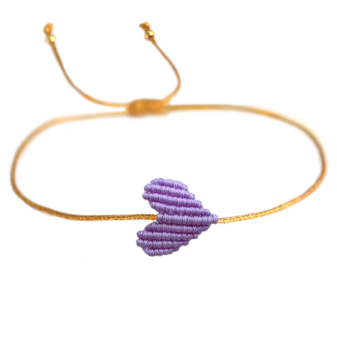 Armband mit goldenem Band und geflochtenem Herz in lila von Love biza. Dank praktischem Schiebeknoten passt das Armband an jedes Handgelenk! 