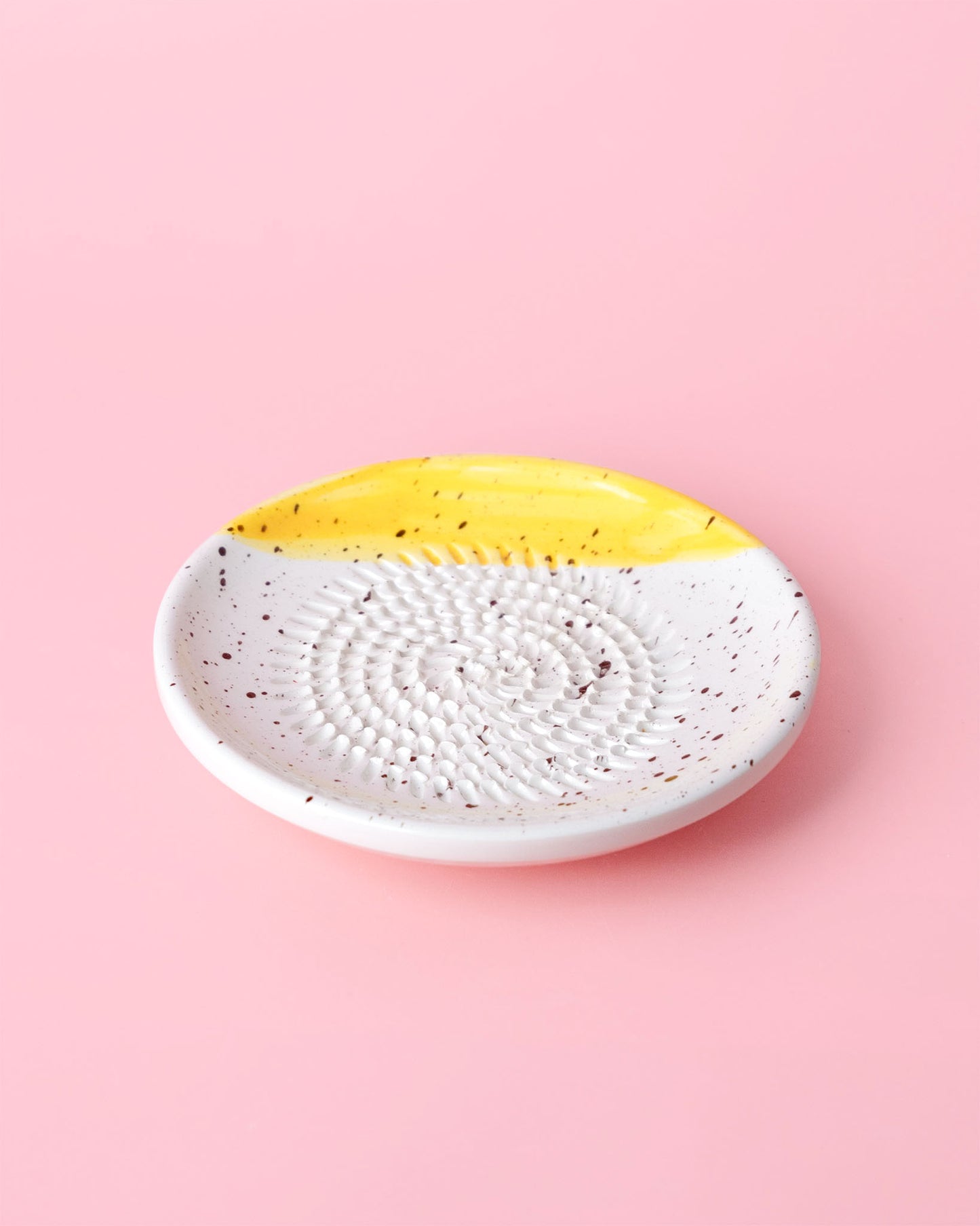 Kleine, handgefertige Keramikreibe mit schwarzen Klecksen und gelbem Highlight - Praktisch, dekorativ und eine schöne Geschenkidee für Feinschmecker.