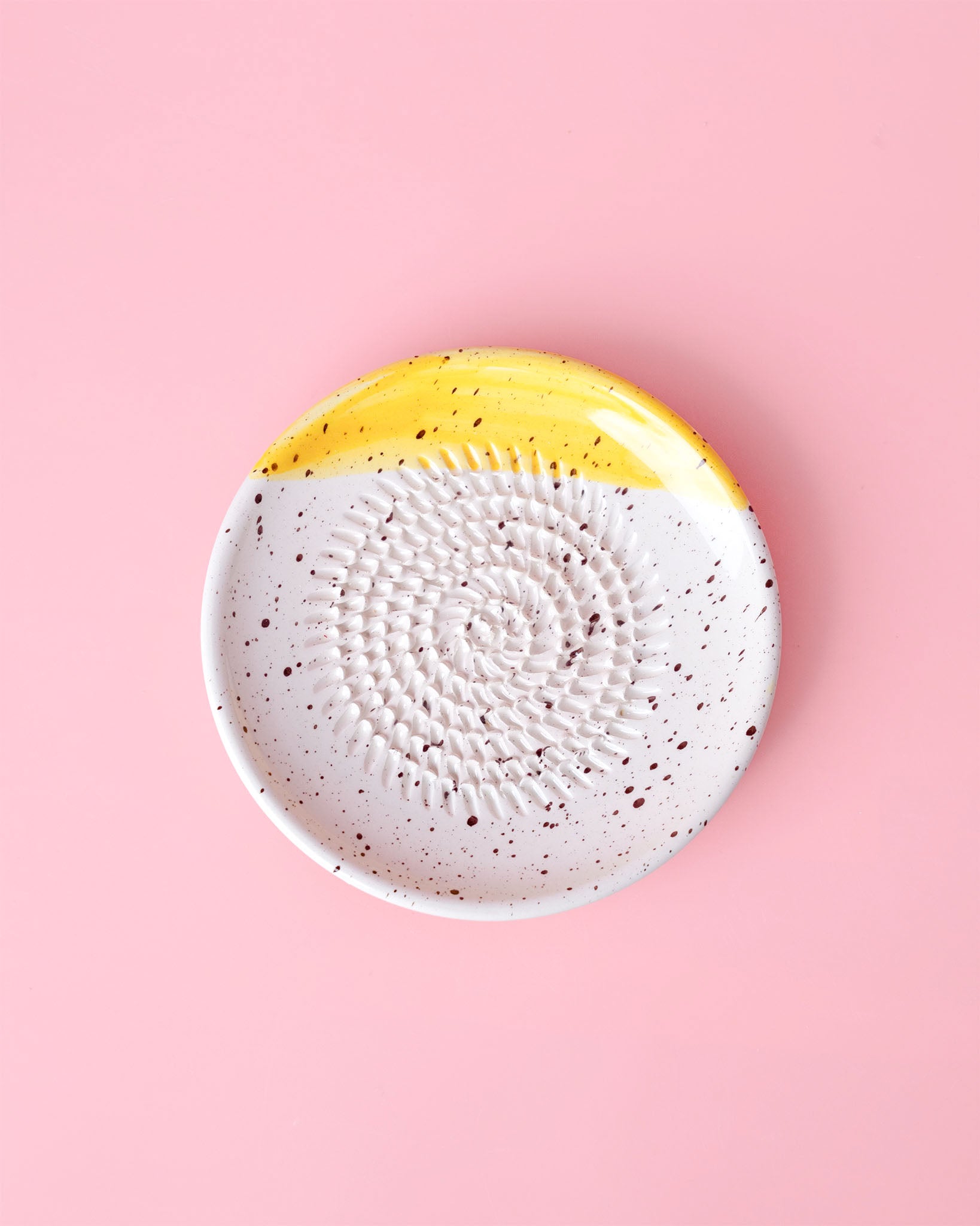 Kleine, handgefertige Keramikreibe mit schwarzen Klecksen und gelbem Highlight - Ideal zum Reiben von Knoblauch, Ingwer oder Schokolade. 