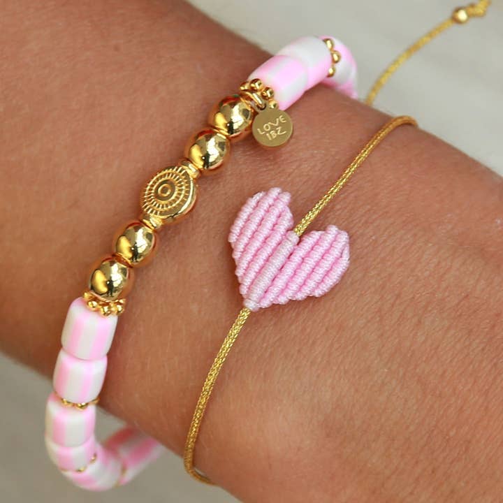 Armband mit goldenem Band und geflochtenem Herz in rosa von Love Ibiza. Dank praktischem Schiebeknoten passt das Armband an jedes Handgelenk! 