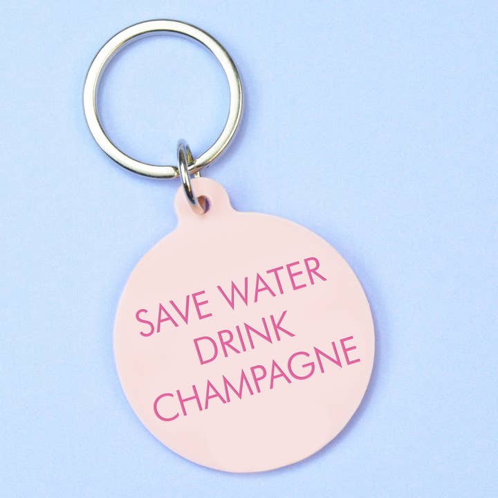 Schlüsselanhänger von Flamingo Candles mit Statement "Save water drink champagne" auf rosa Acryl graviert.